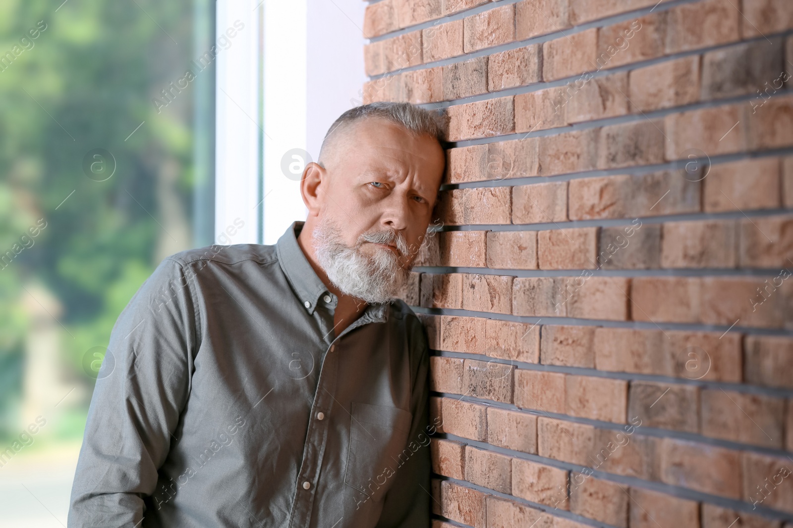 Photo of Senior man in state of depression near brick wall