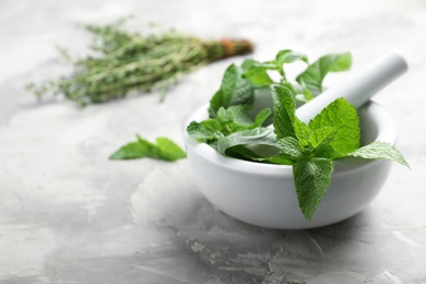 Mortar with fresh green herbs on table