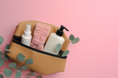 Photo of Preparation for spa. Compact toiletry bag with different cosmetic products and eucalyptus on pink background, flat lay. Space for text