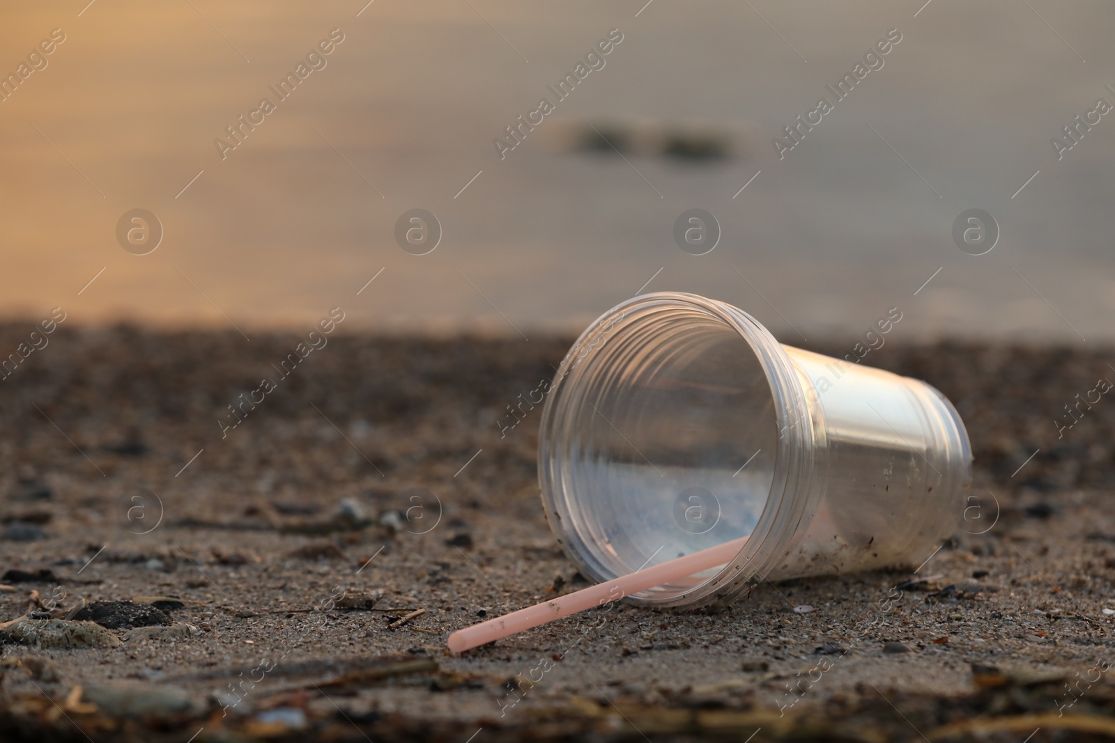 Photo of Used plastic cups and straw at beach, space for text. Environmental pollution concept