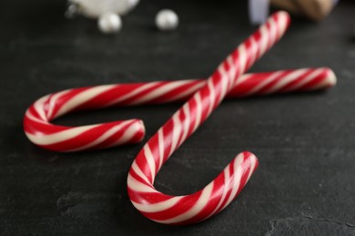 Photo of Sweet Christmas candy canes on black table, closeup