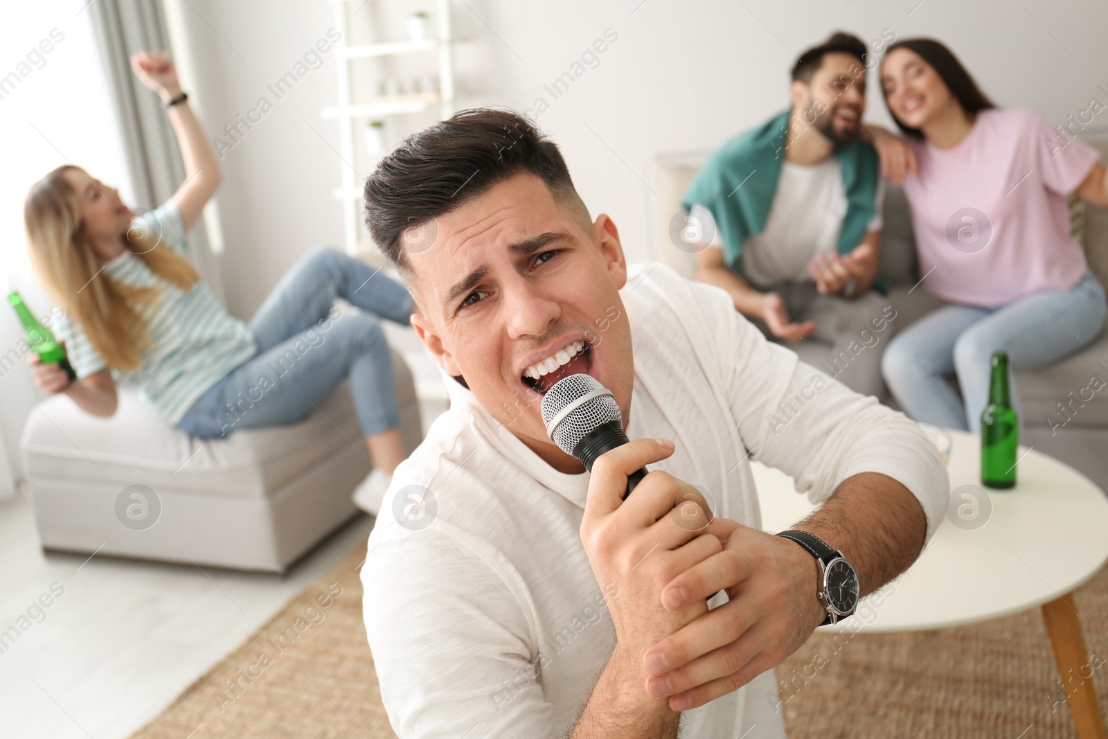 Photo of Man singing karaoke with friends at home