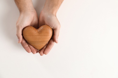 Man holding decorative heart on white background, top view with space for text