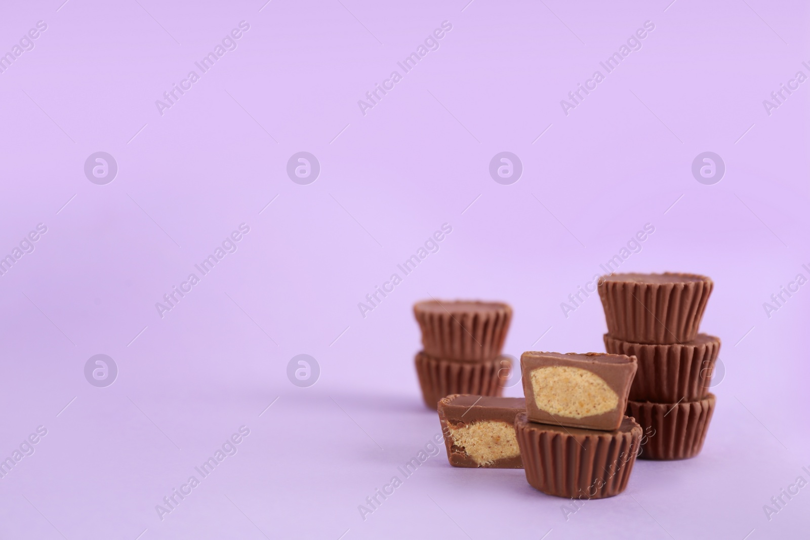 Photo of Sweet peanut butter cups on violet background. Space for text