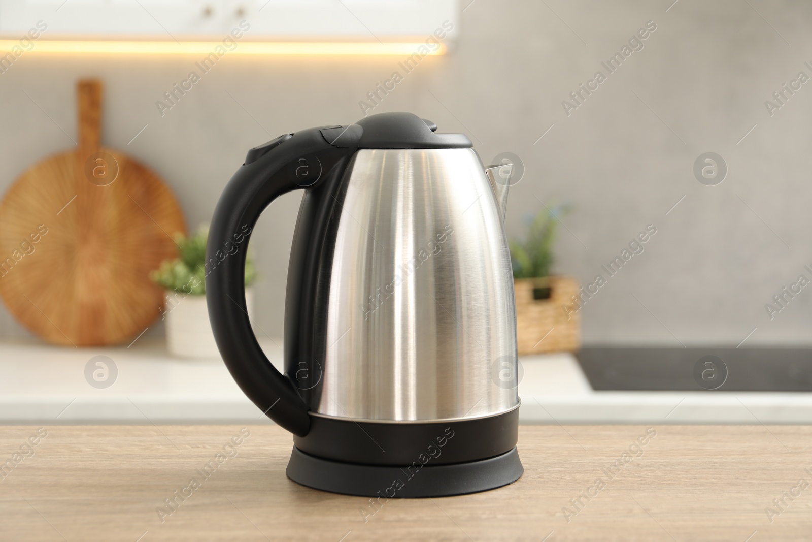 Photo of Modern electric kettle on table in kitchen