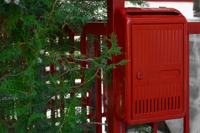 Photo of Red beautiful metal letter box near tree outdoors