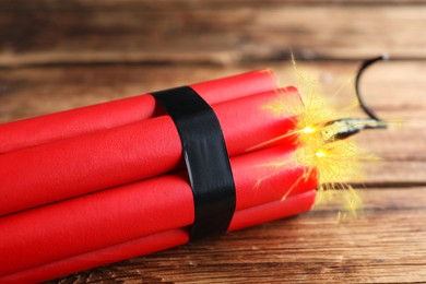 Image of Dynamite bomb with lit fuse on wooden table, closeup