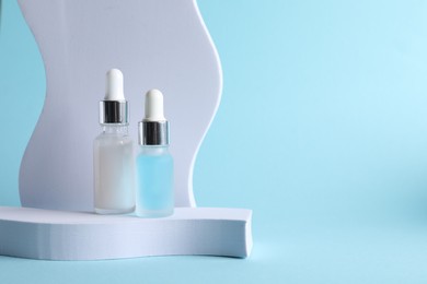 Photo of Stylish presentation of cosmetic serum on light blue background, space for text