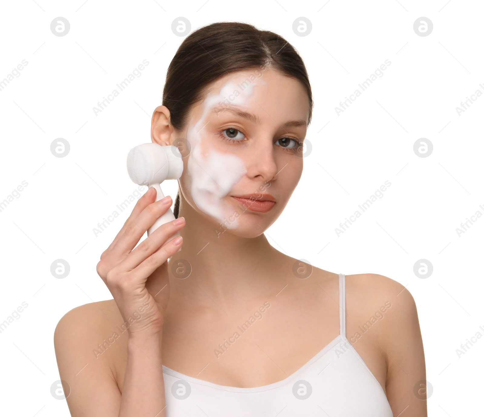 Photo of Young woman washing face with brush and cleansing foam on white background