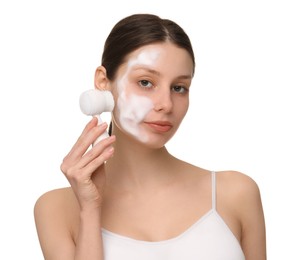 Young woman washing face with brush and cleansing foam on white background