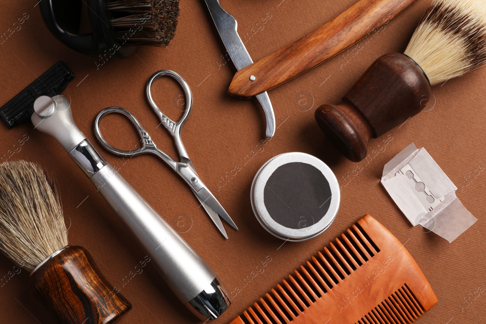 Photo of Moustache and beard styling tools on brown background, flat lay