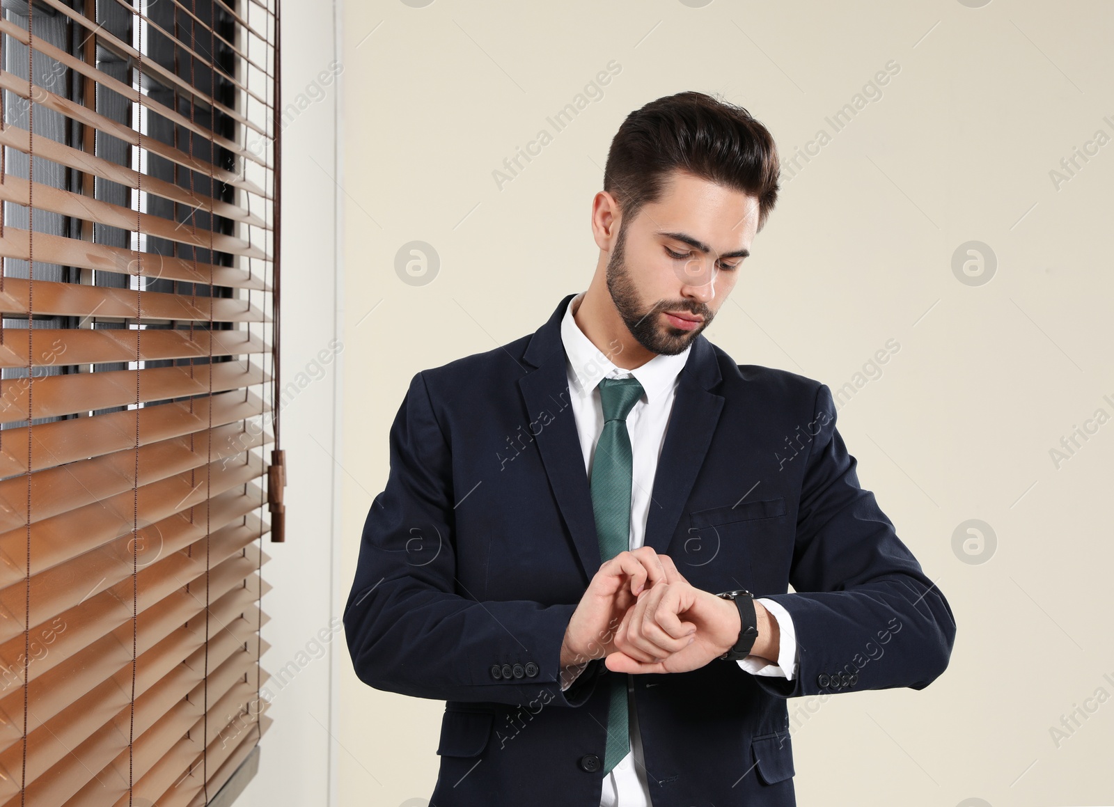 Photo of Portrait of confident businessman checking time at window indoors