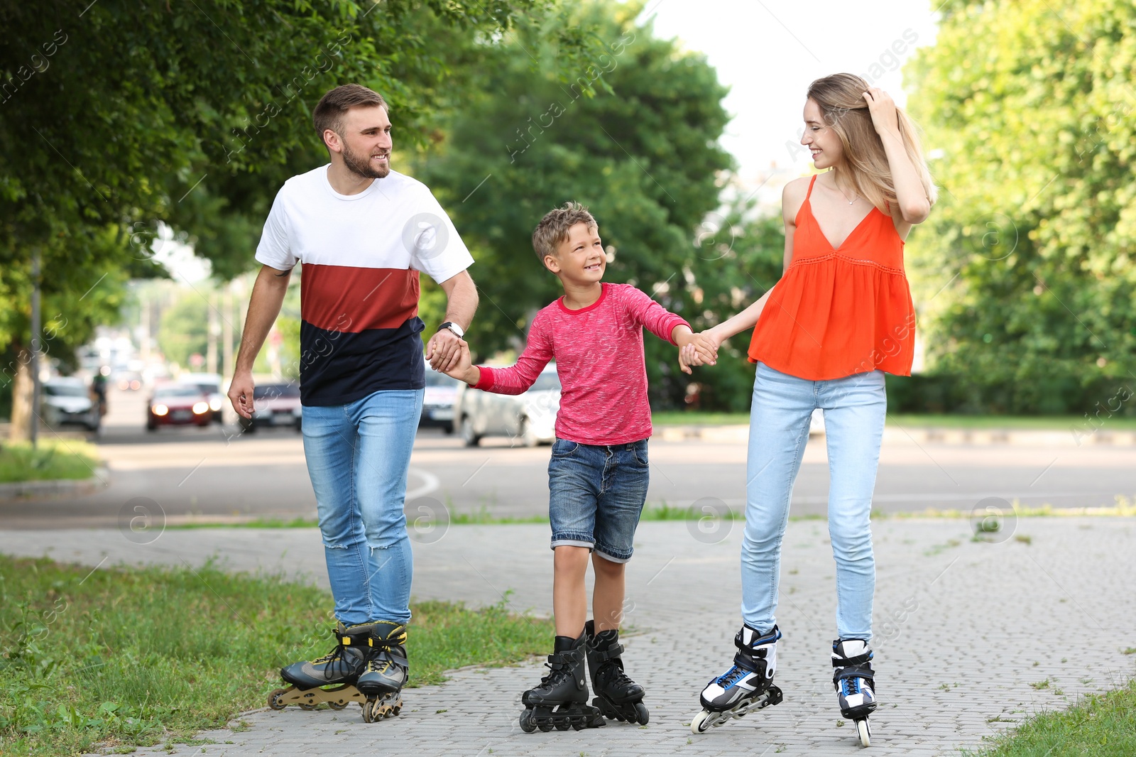 Photo of Young happy family roller skating on city street