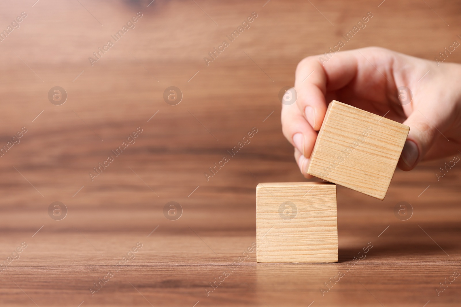 Photo of Woman arranging cubes on wooden background, closeup with space for text. Idea concept