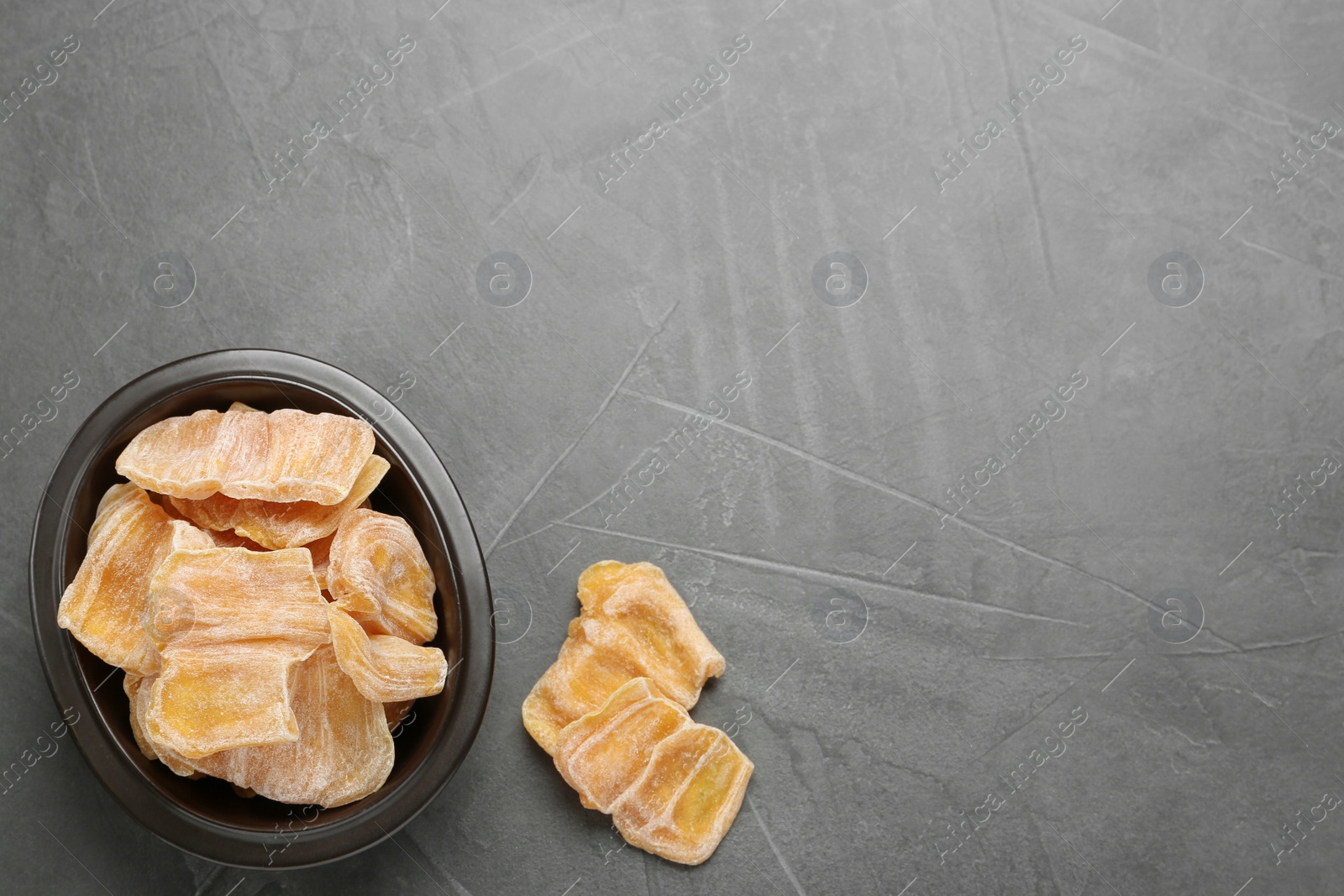 Photo of Delicious dried jackfruit slices on grey table, flat lay. Space for text