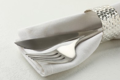 Stylish setting with cutlery and napkin on white textured table, closeup