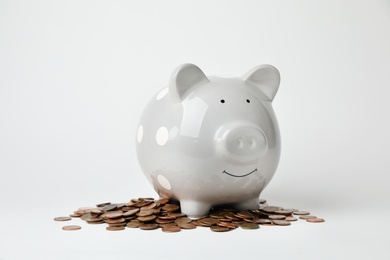 Photo of Cute piggy bank and coins on light background