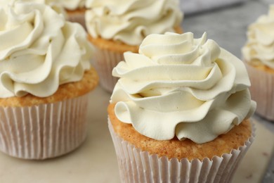 Tasty cupcakes with vanilla cream on table, closeup