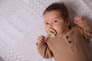 Photo of Cute little baby with pacifier lying on blanket, top view. Space for text