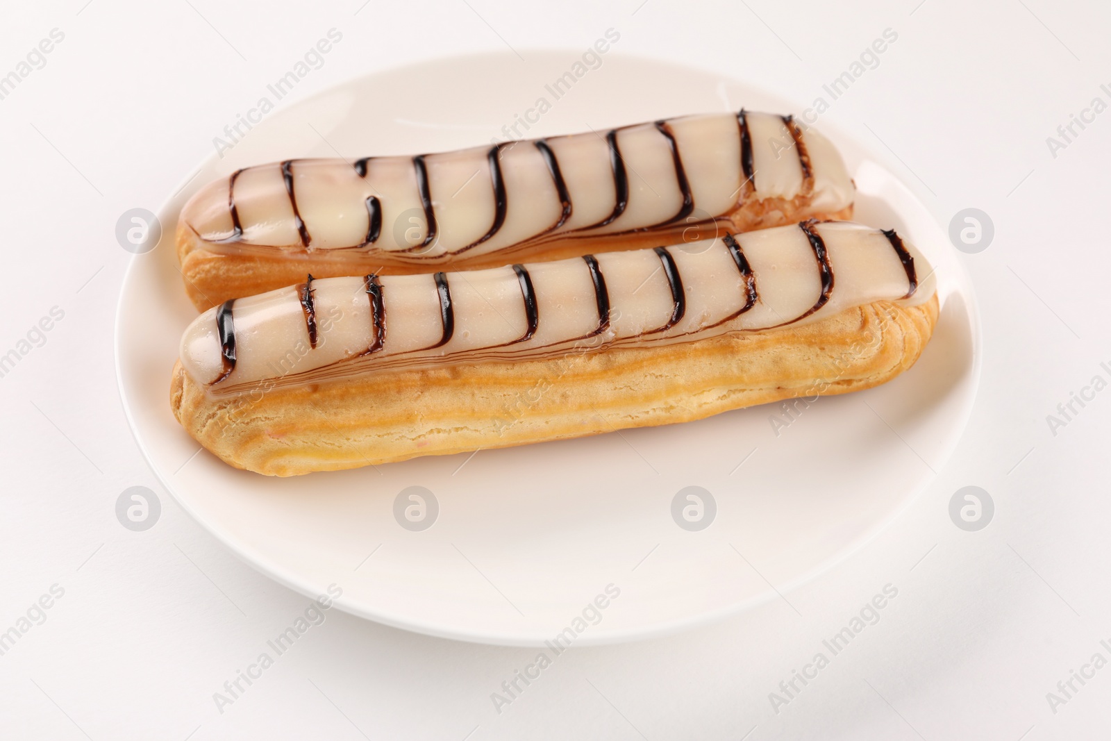 Photo of Delicious eclairs covered with glaze on white background