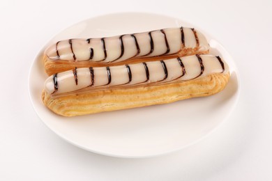 Photo of Delicious eclairs covered with glaze on white background