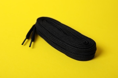 Photo of Black shoe lace on yellow background. Stylish accessory