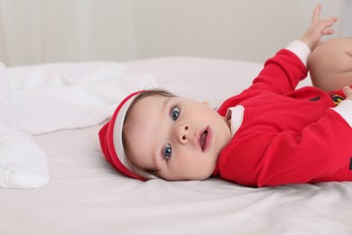 Photo of Cute baby wearing festive Christmas costume on bed