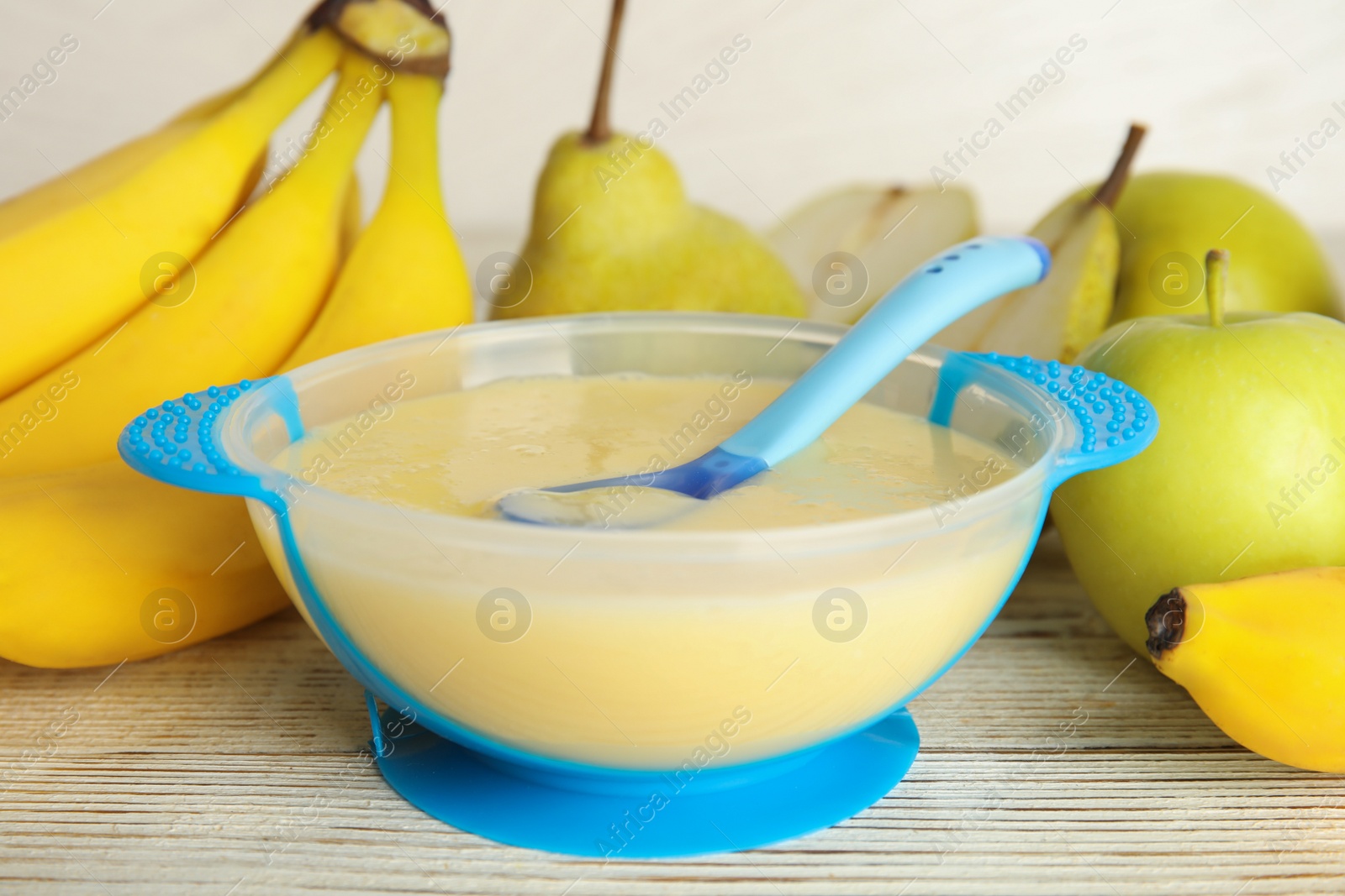 Photo of Baby food in bowl and fresh ingredients on white wooden table