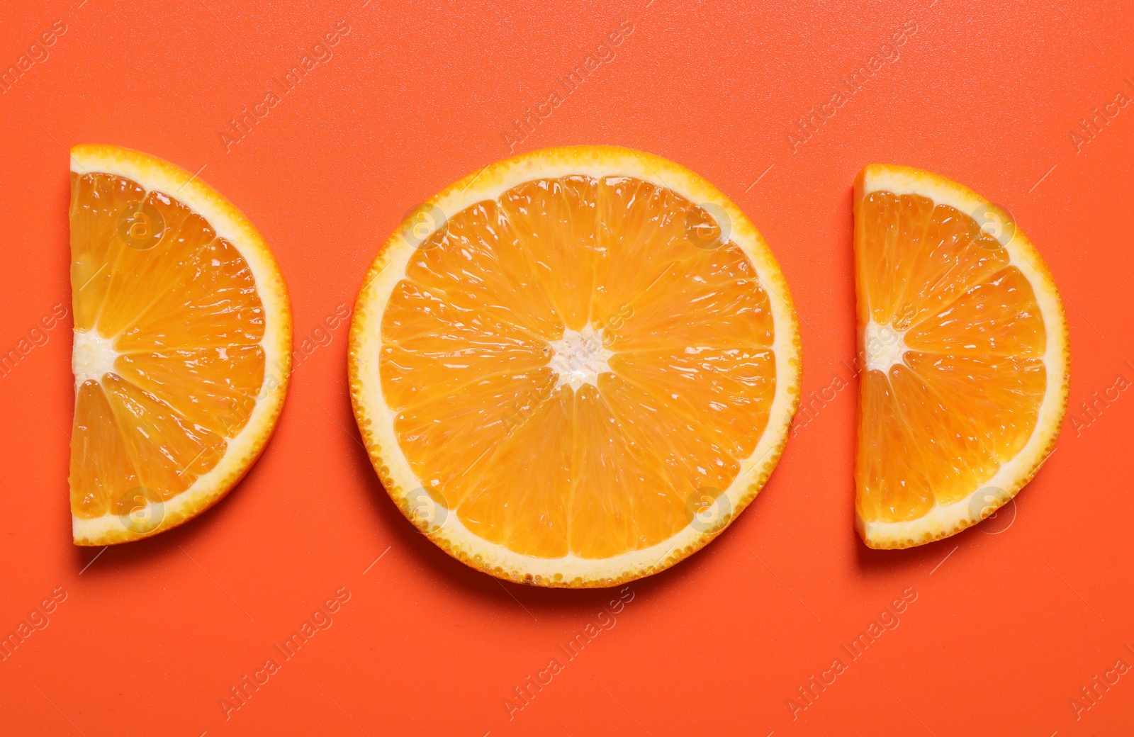 Photo of Slices of juicy orange on terracotta background, flat lay