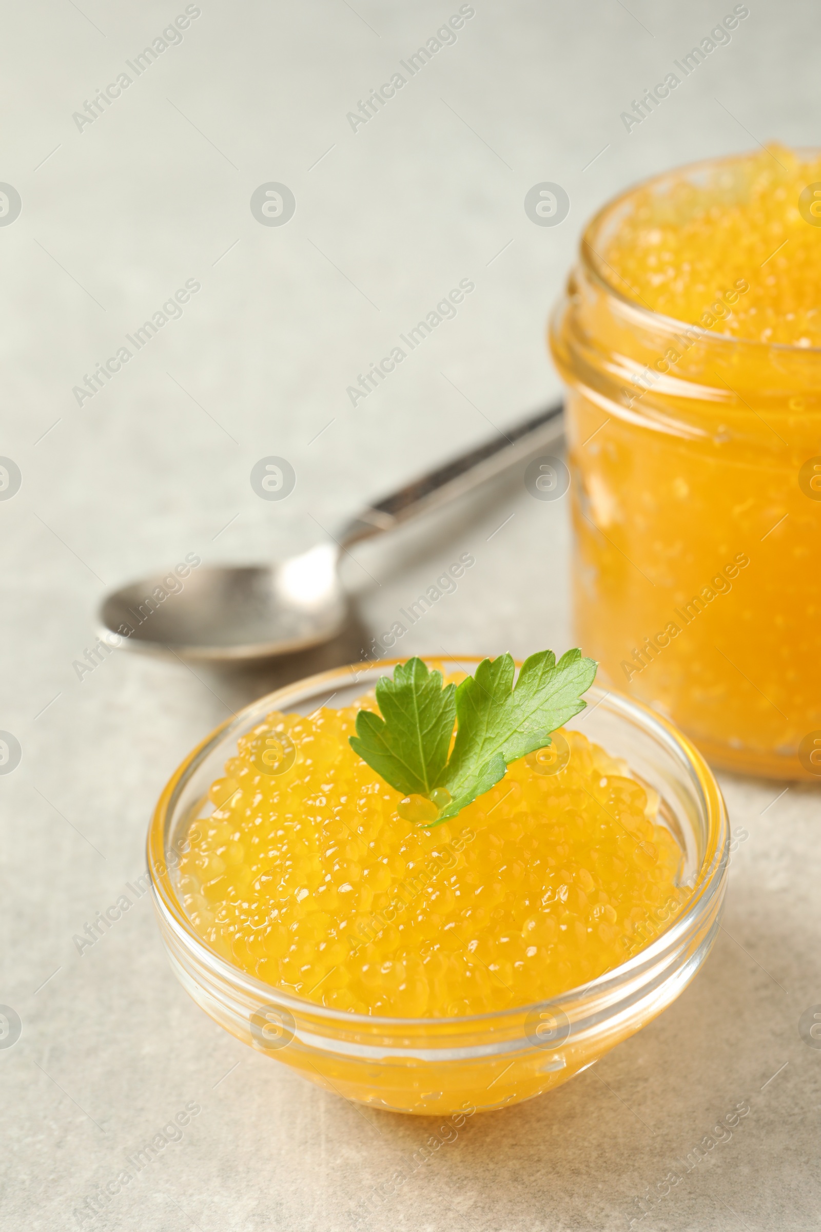 Photo of Fresh pike caviar in bowl, parsley and spoon on light grey table, closeup