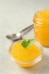 Fresh pike caviar in bowl, parsley and spoon on light grey table, closeup