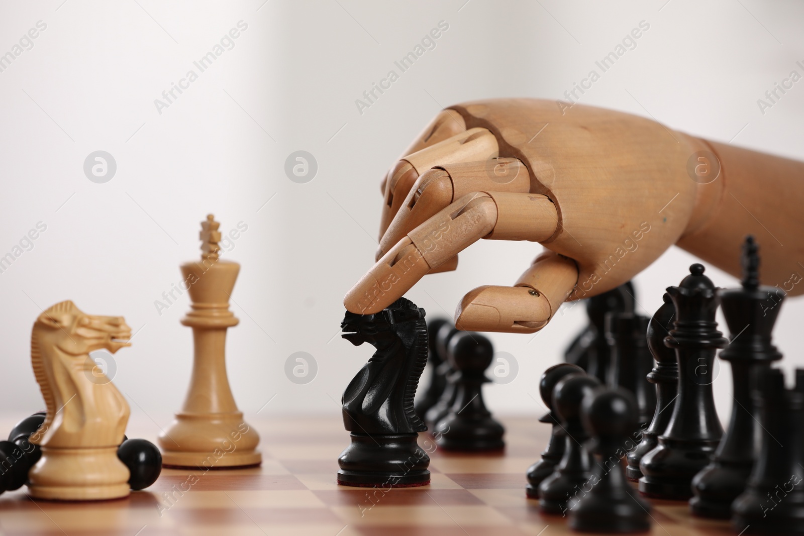 Photo of Robot moving chess piece on board against light background, closeup. Wooden hand representing artificial intelligence