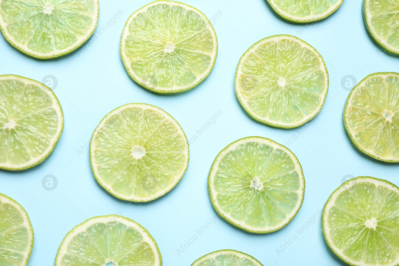 Photo of Fresh juicy lime slices on light blue background, flat lay
