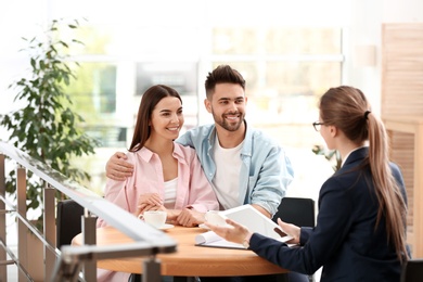 Photo of Female insurance agent working with young couple in office