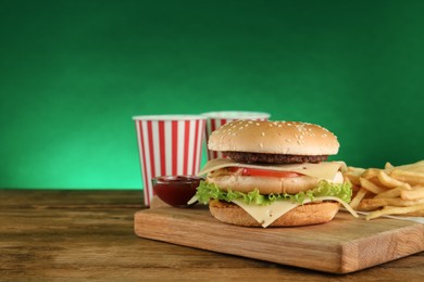 Delicious fast food menu on wooden table against green background. Space for text