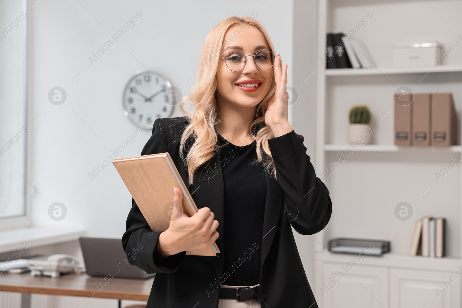 Photo of Portrait of happy secretary with notebook in office