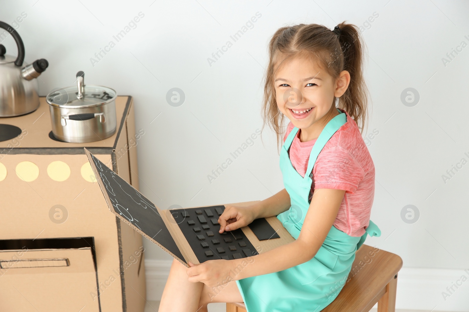 Photo of Little child playing with carton laptop indoors