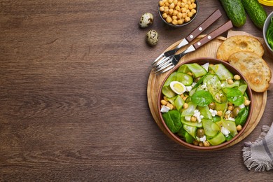 Delicious cucumber salad and toasted bread served on wooden table, flat lay. Space for text