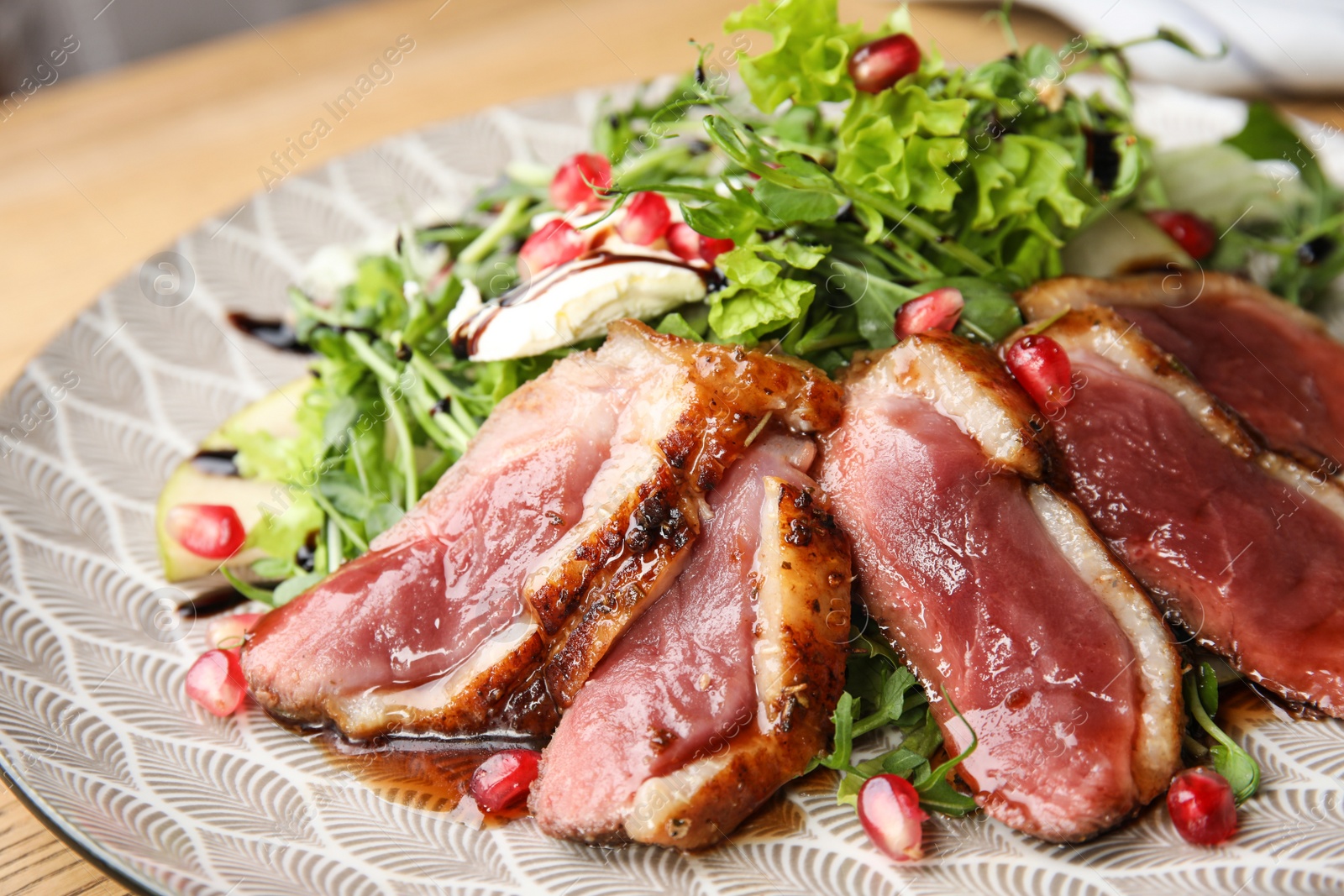 Photo of Delicious salad with roasted duck breast on plate, closeup