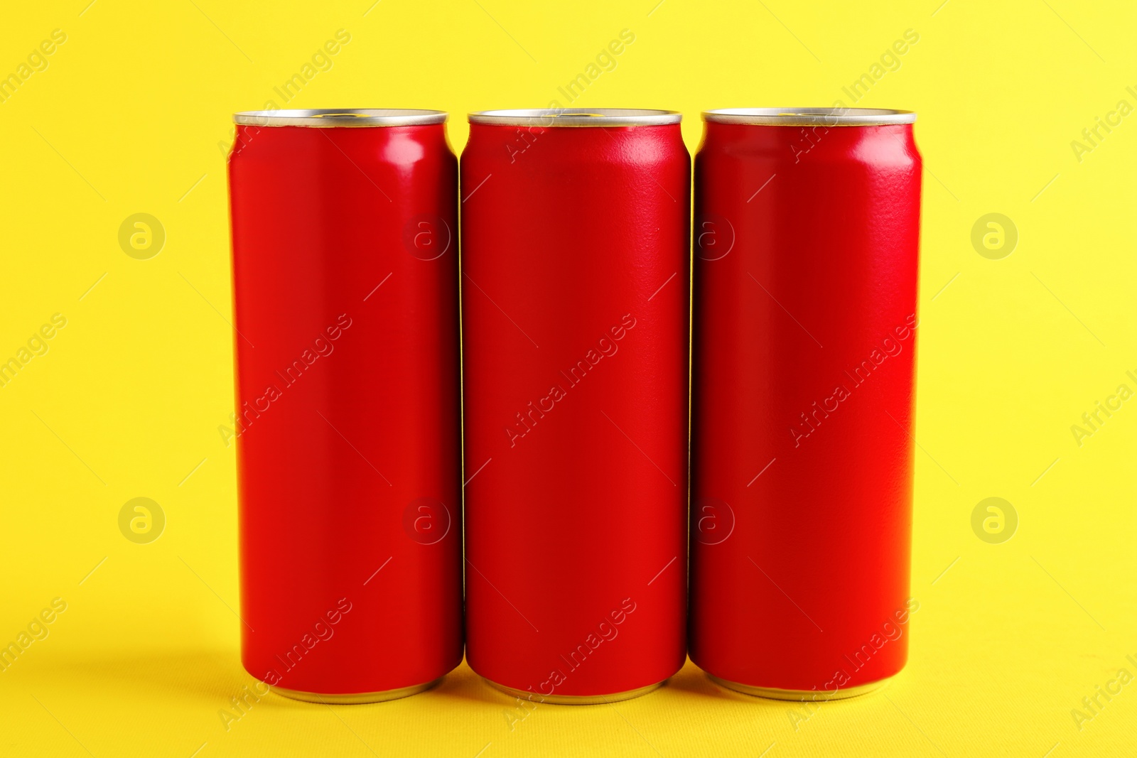 Photo of Energy drinks in red cans on yellow background