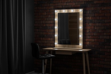 Photo of Mirror with light bulbs, table, chair and curtain in makeup room