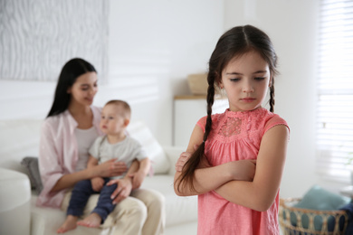Photo of Unhappy little girl feeling jealous while mother spending time with her baby brother at home