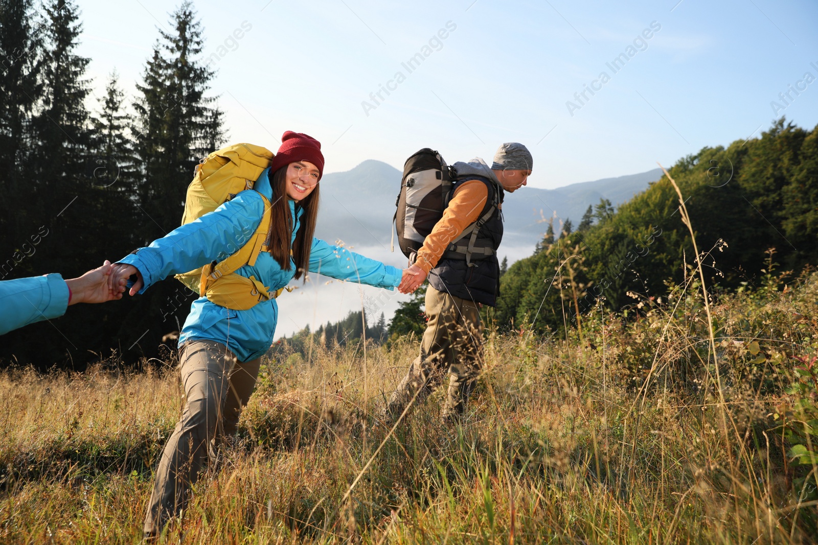 Photo of Tourists with backpacks hiking in mountains on sunny day