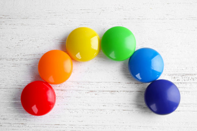 Photo of Bright magnets on white wooden background, flat lay. Rainbow colors