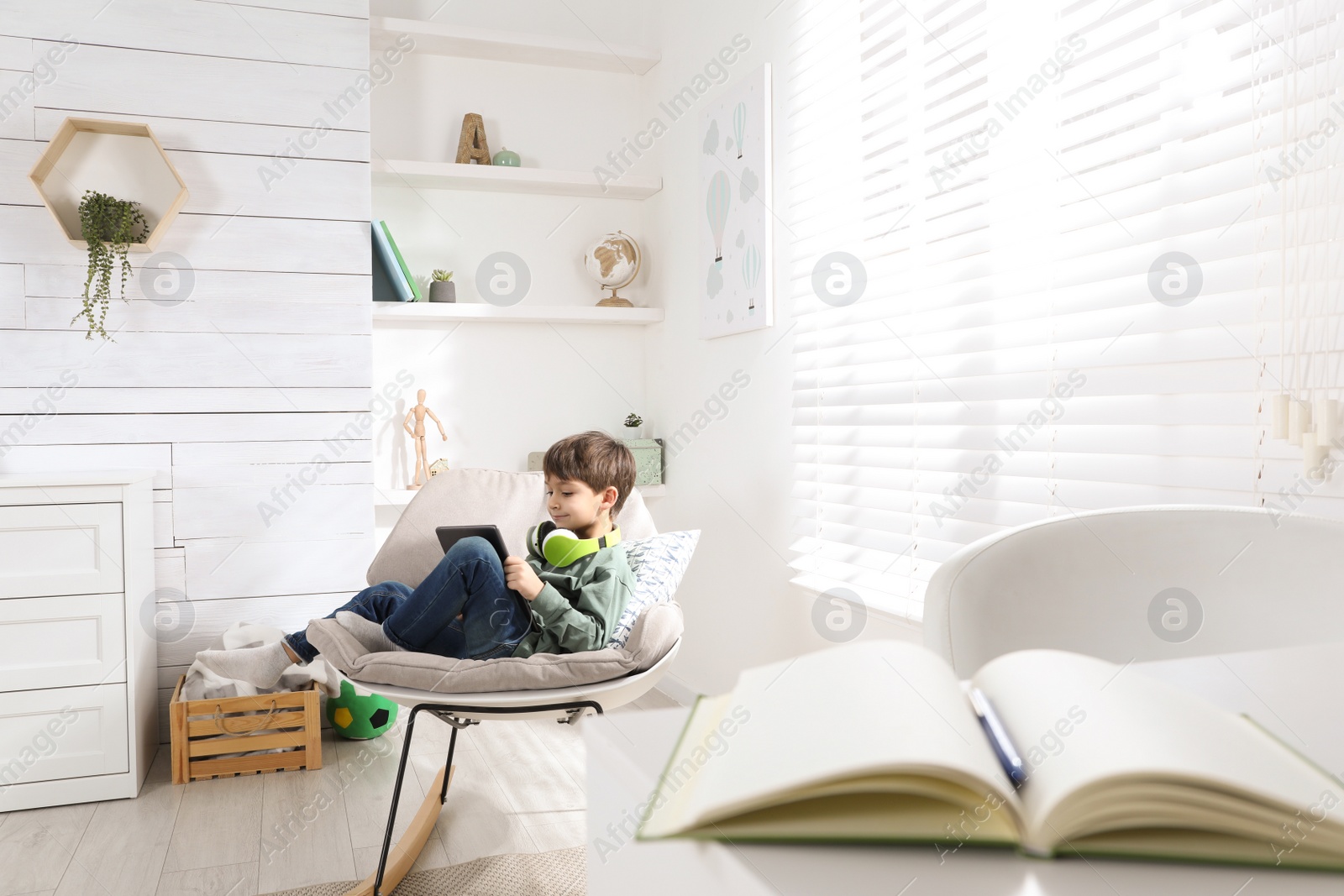 Photo of Cute little boy with modern tablet studying online at home. E-learning