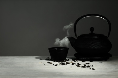 Photo of Oriental teapot and cup on table against grey background, space for text