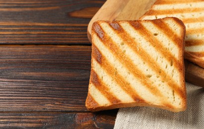 Photo of Slices of tasty toasted bread on wooden table, closeup. Space for text