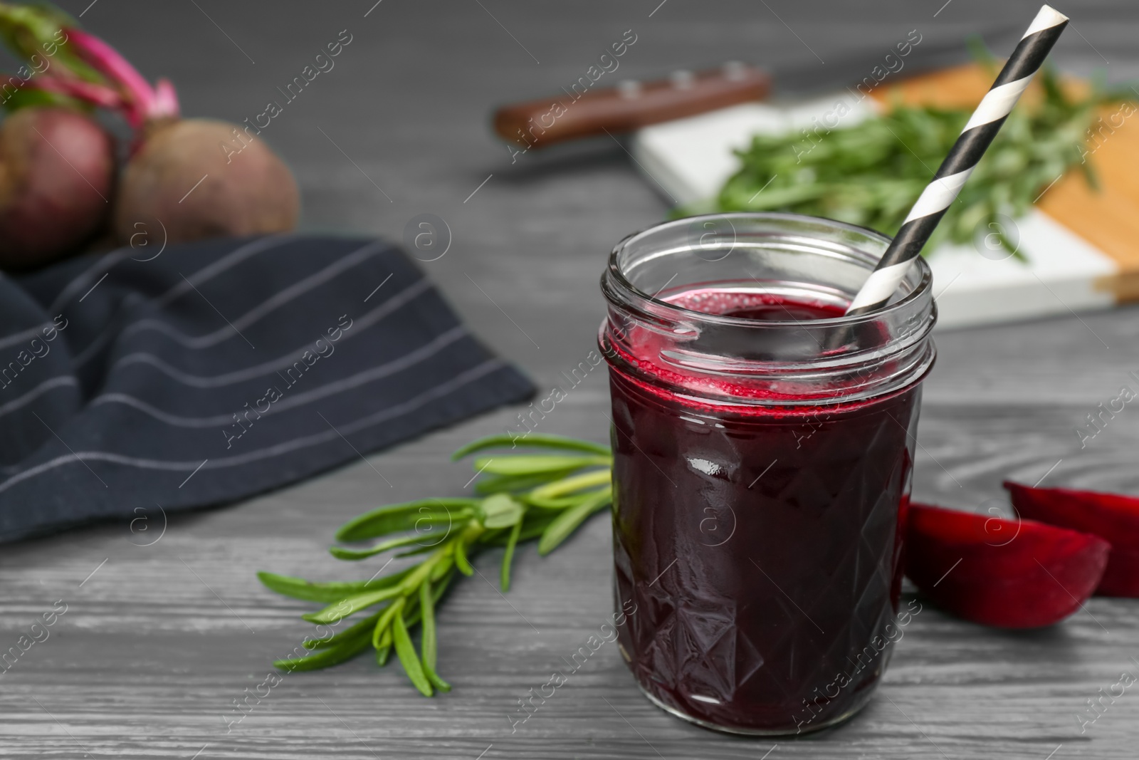 Photo of Fresh beet juice and raw vegetable on grey wooden table. Space for text