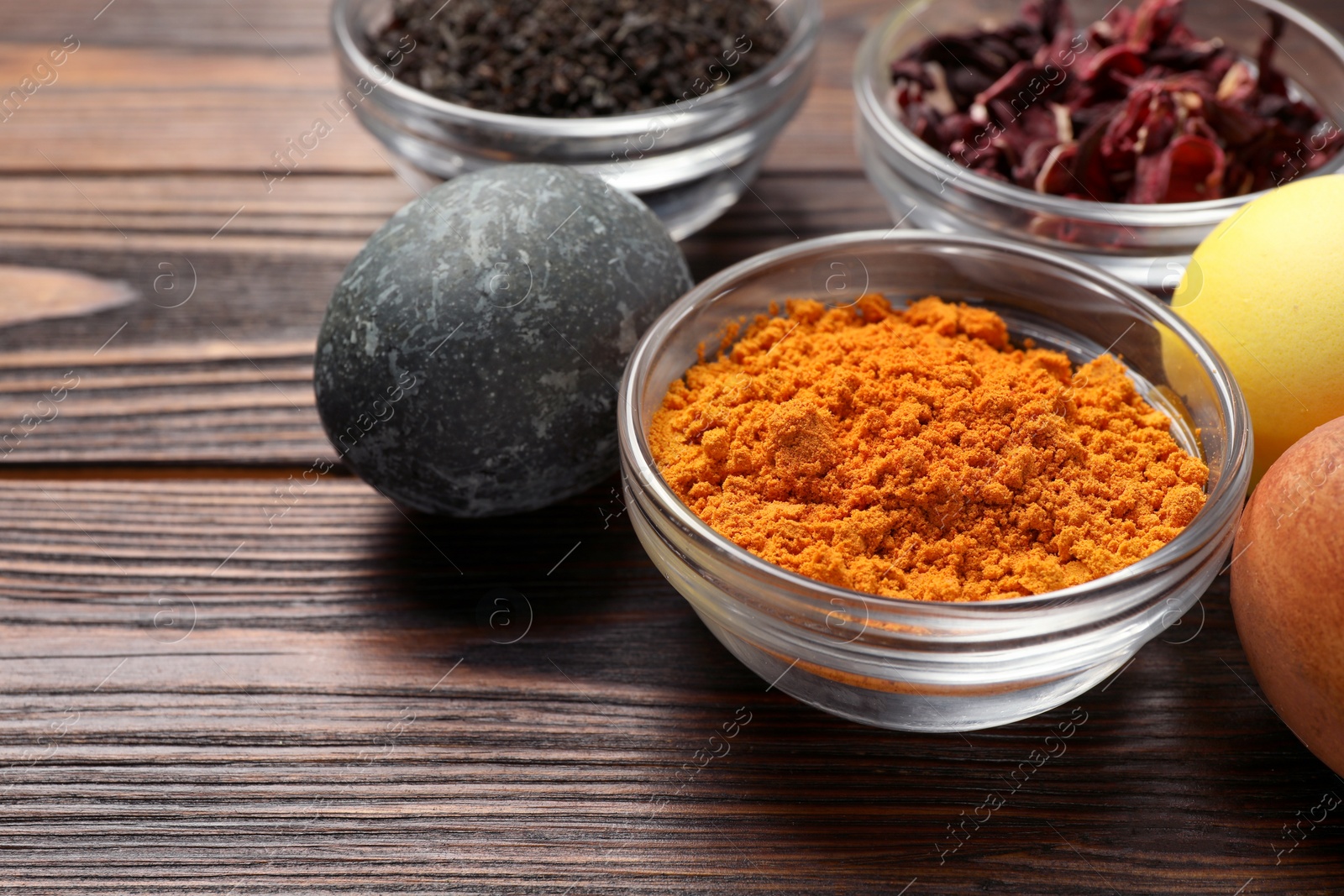 Photo of Painted Easter eggs with natural organic dyes (turmeric, hibiscus, tea) on wooden table, closeup. Space for text