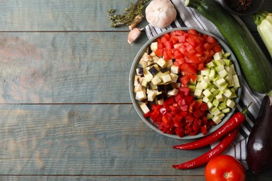 Cooking delicious ratatouille. Fresh ripe vegetables and plate on light blue wooden table, flat lay. Space for text